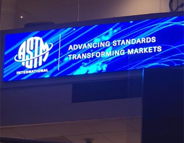 Digital display sign showing the ASTM International logo with the text 'Advancing Standards, Transforming Markets.'