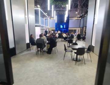 Business discussions in a modern exhibition hall breakout space.